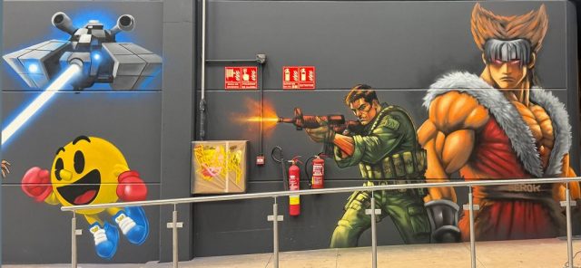 Graffiti con Pac-Man, una nave futurista, un soldado y un guerrero inspirado en videojuegos arcade.