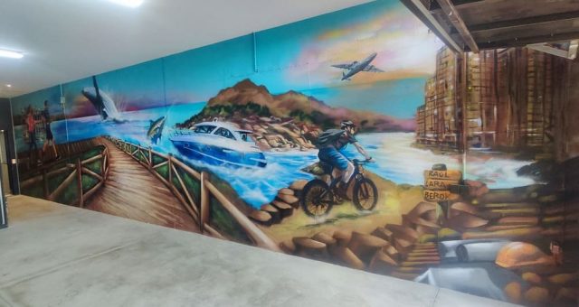 Mural panorámico con mar, montaña, avión, embarcación y ciclista en un paisaje fantástico.
