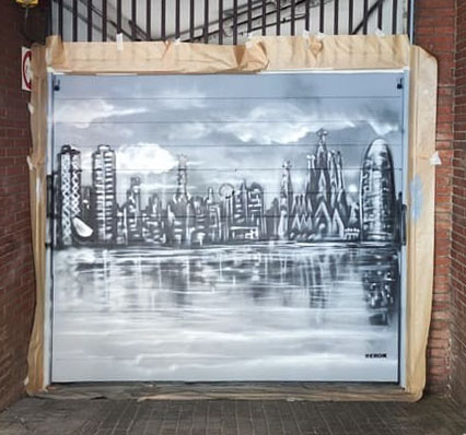 Graffiti en persiana con el skyline de Barcelona pintado en blanco y negro.