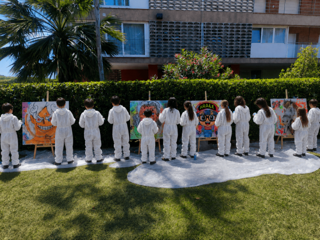 Niños pintando cuadros de anime con spray durante un taller de graffiti.