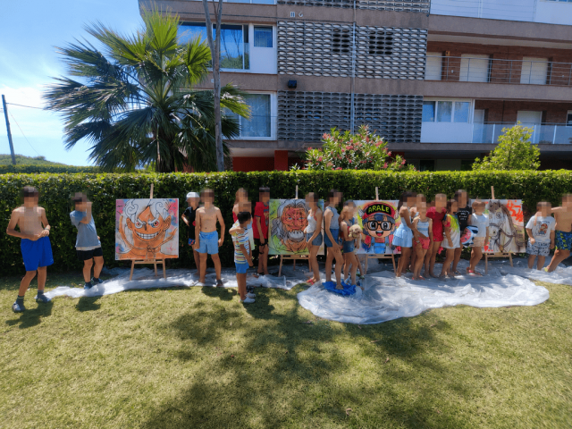 Grupo de participantes junto a los cuadros terminados durante un taller de graffiti infantil.