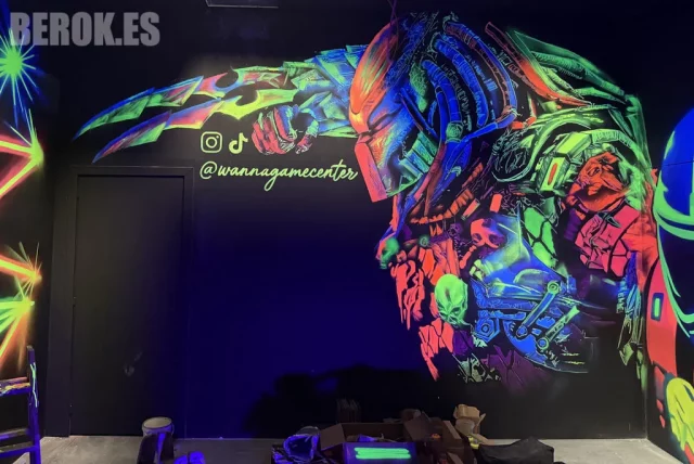Mural Fluorescente de Predator - Graffiti UV Reactivo en Game Center Mural fluorescente de Predator pintado con sprays UV en sala de juegos, efecto glow bajo luz negra