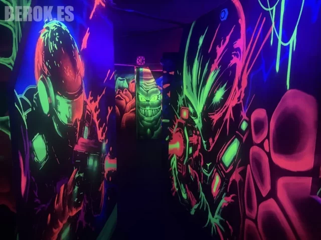 Pasillo Laser Tag con Alien y Predator fluorescentes. Pasillo de Laser Tag con graffitis fluorescentes de Alien y Predator bajo luz ultravioleta.