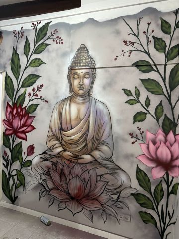 Buda y flores de loto en una pared interior Mural de Buda sentado sobre una flor de loto, rodeado de tallos verdes y flores rosas.