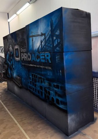 Vista lateral de una superficie decorada en azul con el logotipo de Grupo Proacer y elementos de temática industrial.