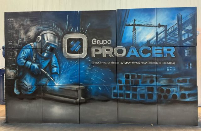 Vista frontal del mural de Grupo Proacer con un soldador, chispas de luz y piezas y estructuras industriales pintadas.