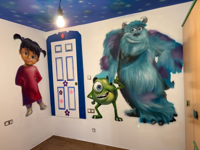 Boo, Mike Wazowski y Sulley pintados junto a una puerta azul en la pared de una habitación infantil.