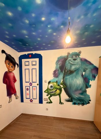 Vista cercana de Boo, Mike y Sulley pintados bajo un techo azul con pequeños puntos de luz en una habitación infantil.