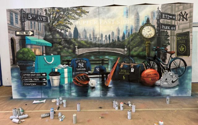 Mural de Central Park y Nueva York con botes de pintura y herramientas en el suelo delante de la obra.