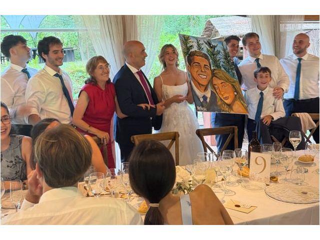 Grupo posando para un retrato durante un evento Grupo de personas posa alrededor de una mesa en un espacio con techo de madera mientras una persona dibuja en primer plano.